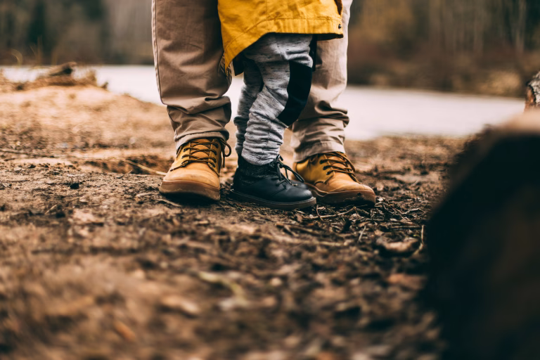 Father and son walking on a leafy path together